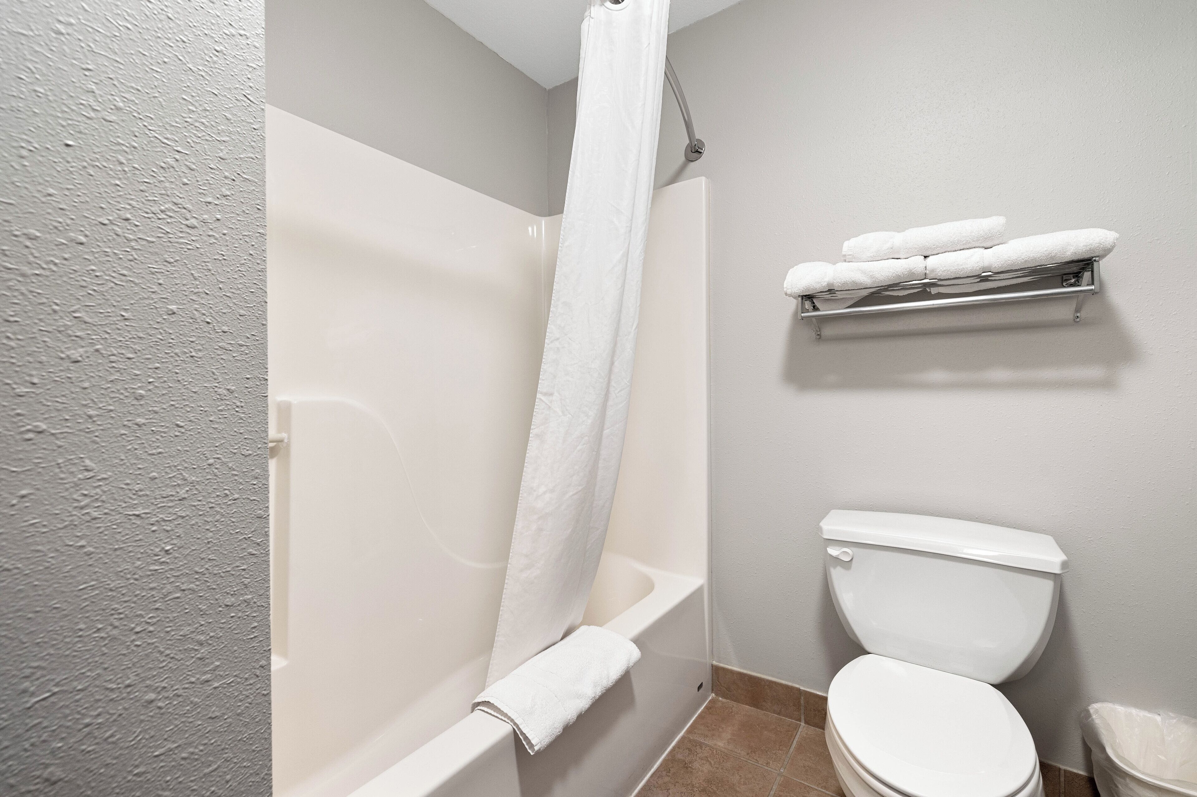 A bathroom with a bathtub, toilet, and a towel rack with towels.