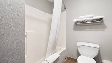 A bathroom with a bathtub, toilet, and a towel rack with towels.