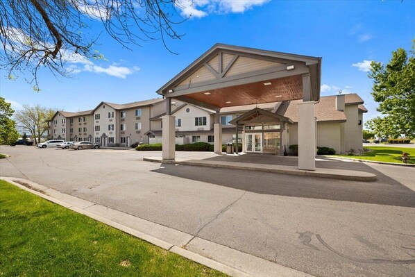 A multi-story hotel with a covered entrance and a parking lot.