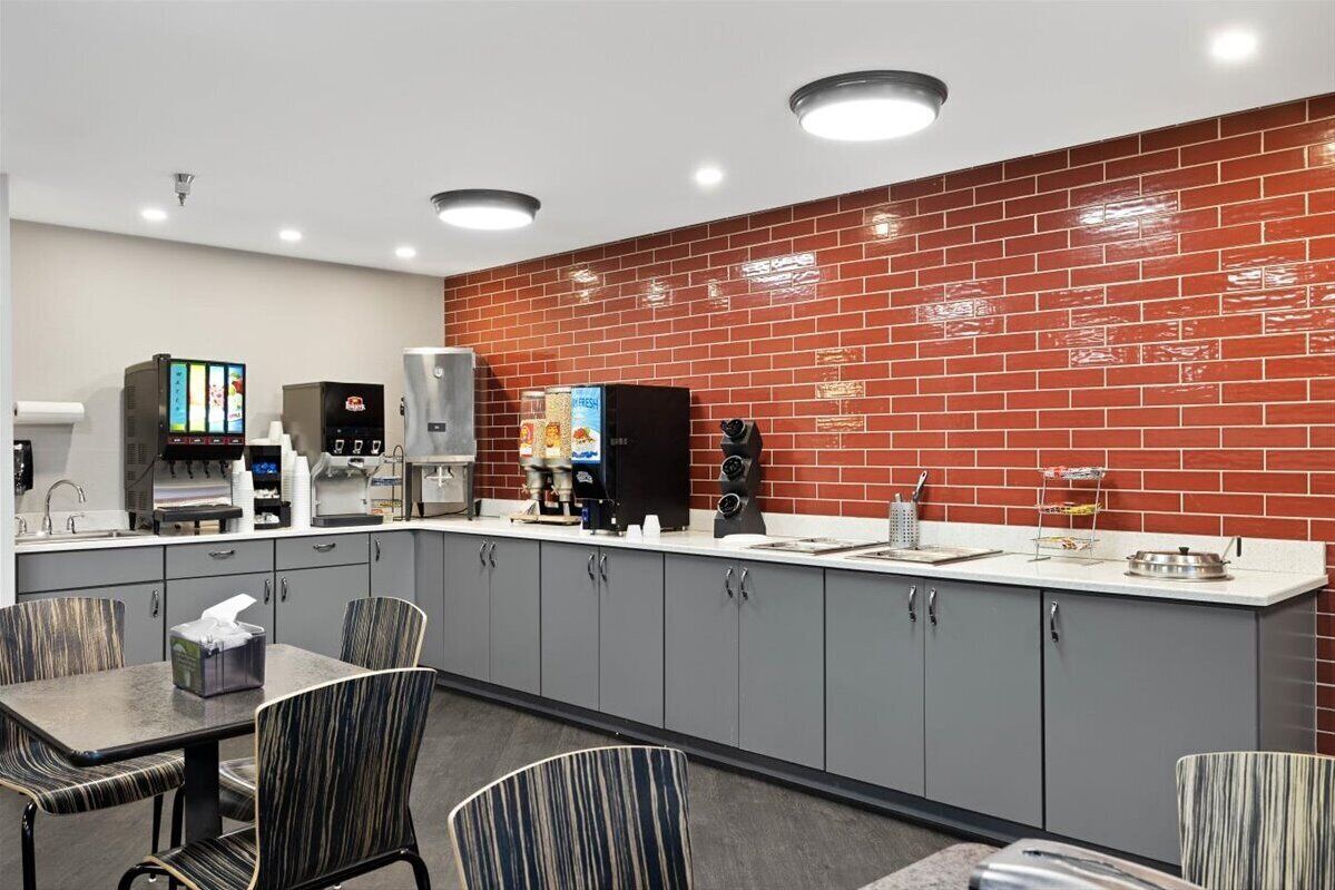 A modern kitchen with grey cabinets, a red brick backsplash, and a coffee machine.