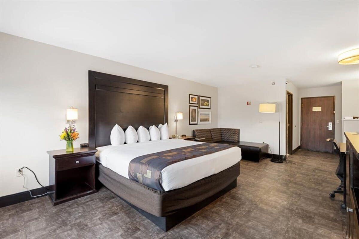 A hotel room with a large bed, bedside tables, a desk, and a chair.