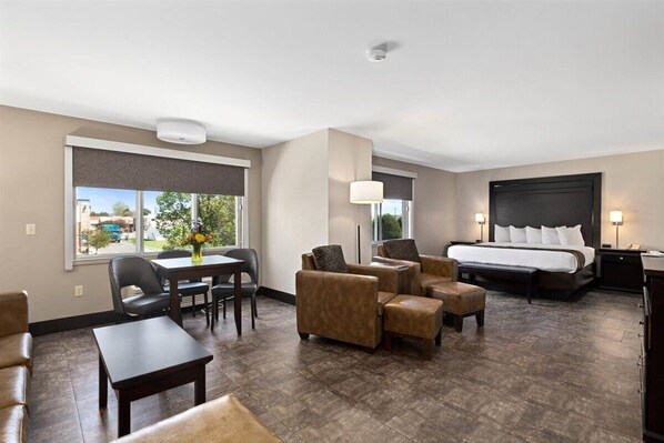 A hotel room with a bed, a desk, a chair, a sofa, and a dining table.