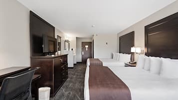 A hotel room with a large bed, a desk with a computer, a TV, and a dresser.