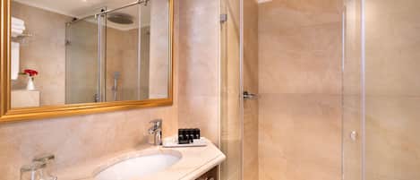 A modern bathroom with a glass-enclosed shower, a large mirror, and a marble sink.
