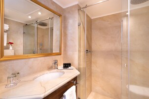 Une salle de bain moderne avec une douche à l’italienne, un grand miroir et un lavabo en marbre.