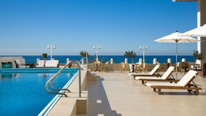 A pool area with lounge chairs and umbrellas, overlooking the ocean. - Orchid Tel Aviv (Tel Aviv)