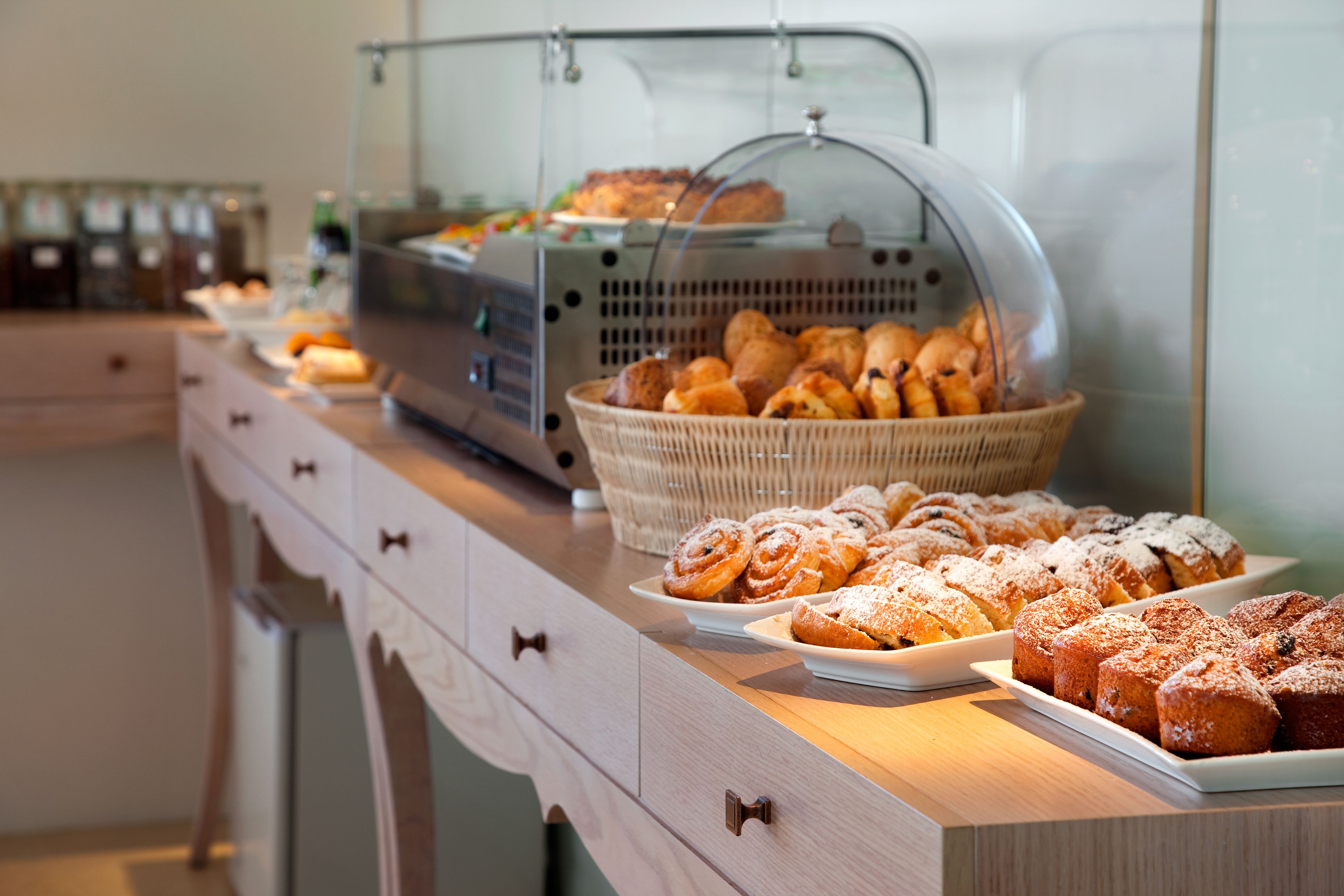 A buffet counter with various pastries and baked goods displayed on plates and in baskets.