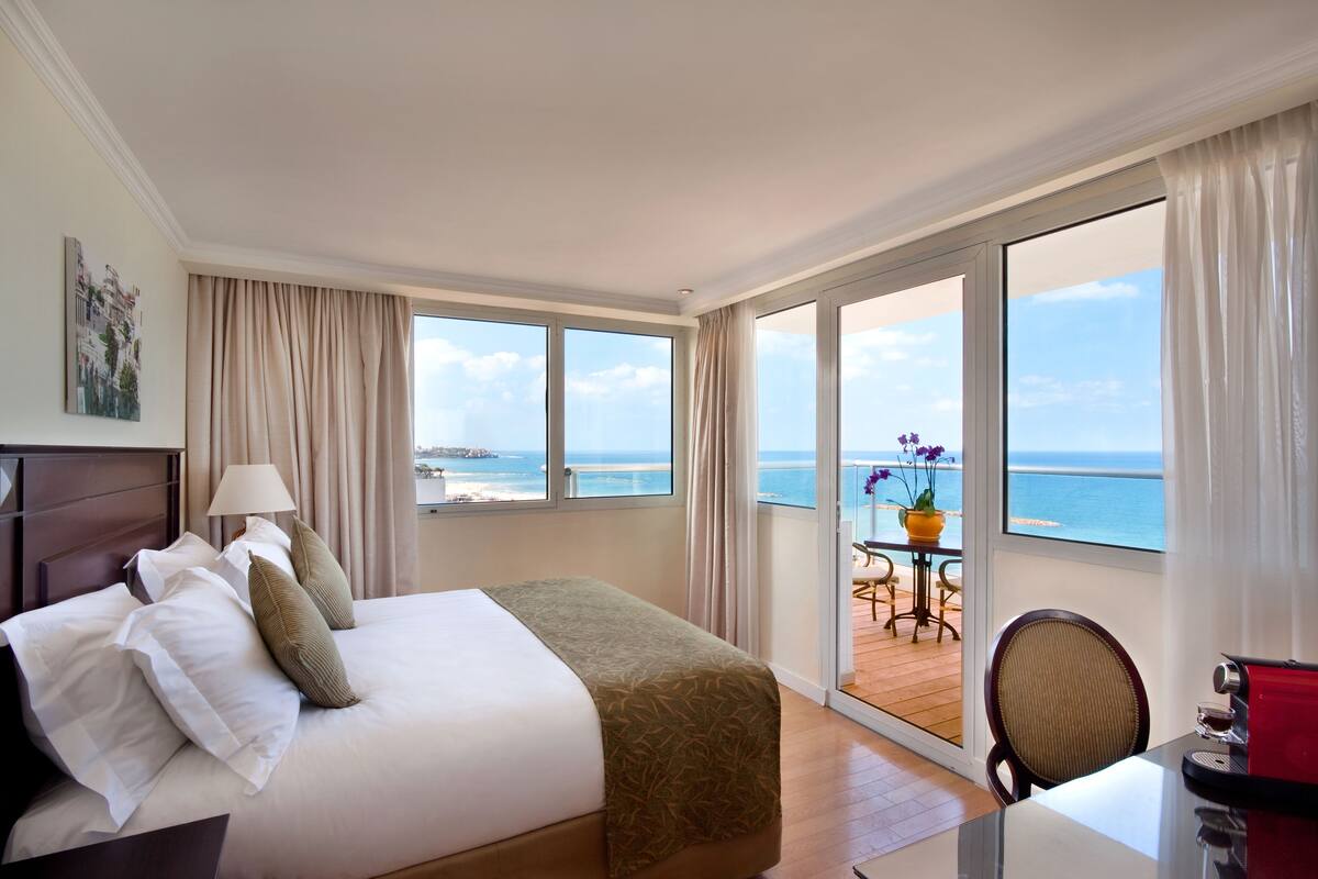 A hotel room with a bed, a desk, and a view of the ocean.