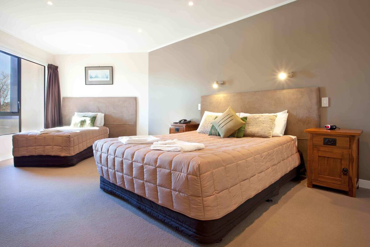 Une chambre avec deux lits, une table de chevet et une commode.