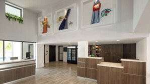 A spacious lobby with a reception desk, wooden flooring, and a large window.