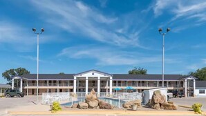 A motel with a pool area, large rocks, and a clear blue sky. - Relax Inn Mineral Wells (Mineral Wells)