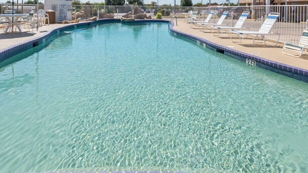 A clear swimming pool with lounge chairs and a tiled deck. - Relax Inn Mineral Wells (Mineral Wells)