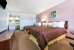 Una habitación de hotel con dos camas, un aparador, un escritorio y una televisión.