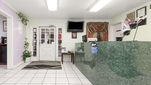 A reception area with a marble counter, a television mounted on the wall, and a door with a glass panel. - Relax Inn Mineral Wells (Mineral Wells)