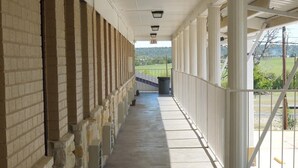 A covered corridor with stone walls and a concrete floor, leading to an exit sign. - Relax Inn Mineral Wells (Mineral Wells)