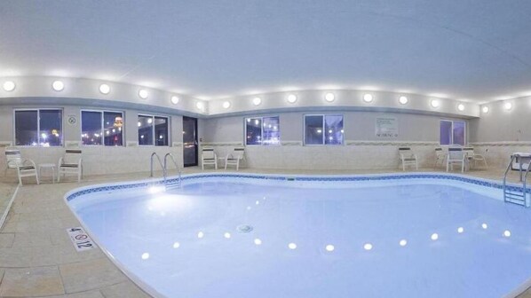 A swimming pool with a tiled deck, surrounded by windows and chairs. - Holiday Inn Express Jamestown by IHG (Jamestown)