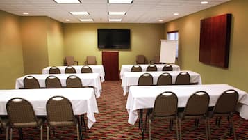 A conference room with multiple tables and chairs, a flat-screen TV, and a whiteboard.