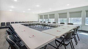 Un salón de conferencias con una larga mesa, sillas y ventanas.