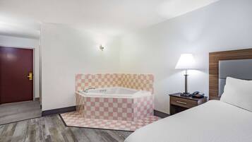 Ein Hotelzimmer mit Schachbrettmuster-Boden, einem großen Bett, einem Nachttisch mit Lampe und einem Badezimmer mit Schachbrettmuster-Wand und einer Badewanne.