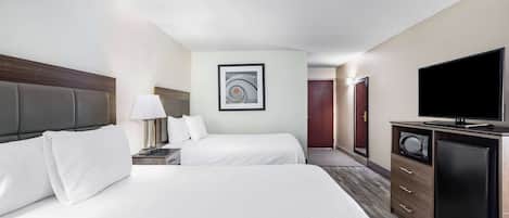 Une chambre d’hôtel avec deux lits, une télévision, un four à micro-ondes et une œuvre d’art encadrée au mur.