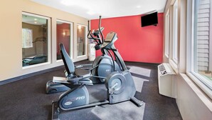 Un gimnasio con máquinas de cardio y una pantalla de televisión en la pared.