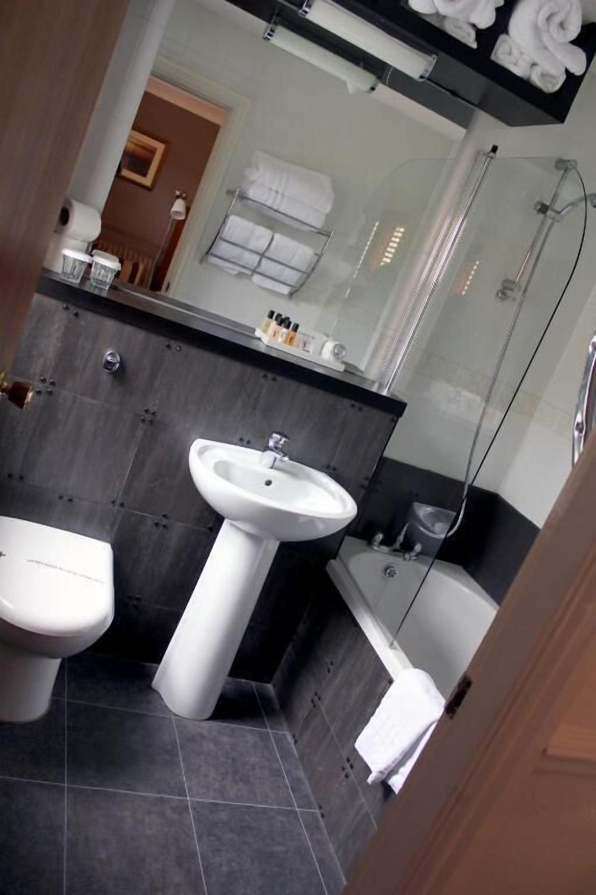 A modern bathroom with a bidet, a sink, and a glass-enclosed shower.