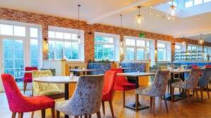 A restaurant with brick walls, large windows, and colorful chairs. - Gomersal Park Hotel (Cleckheaton)