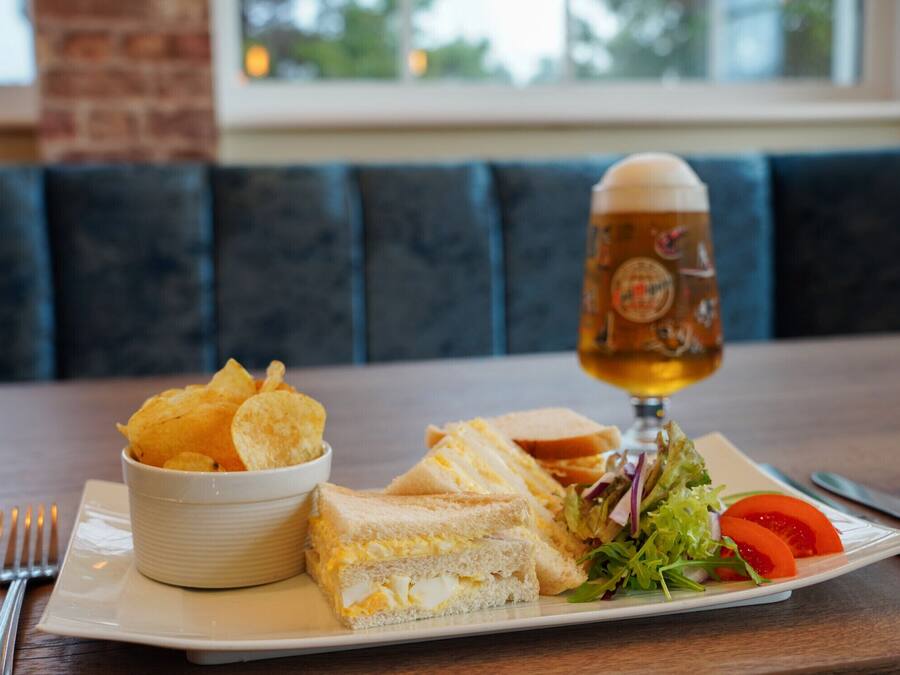 Un plato con sándwiches, papas fritas y una ensalada, junto a una cerveza en la mesa.