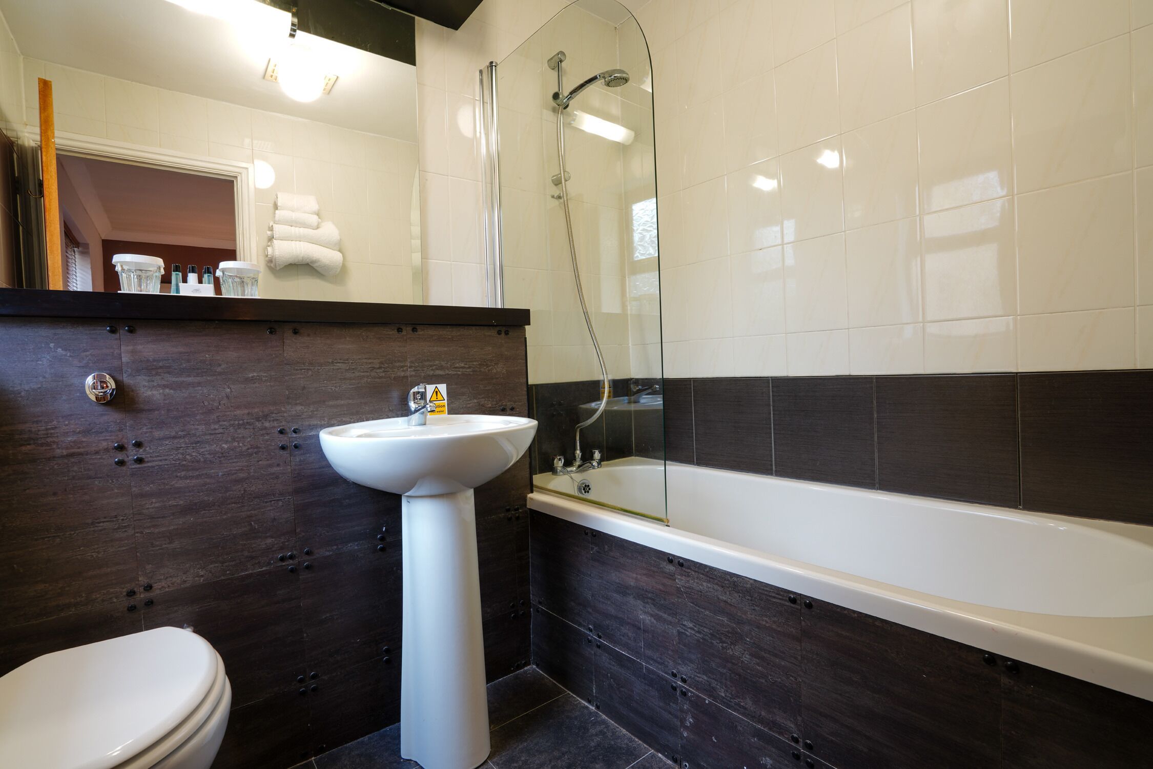 Et moderne badeværelse med hvid vask, badekar og toilet.