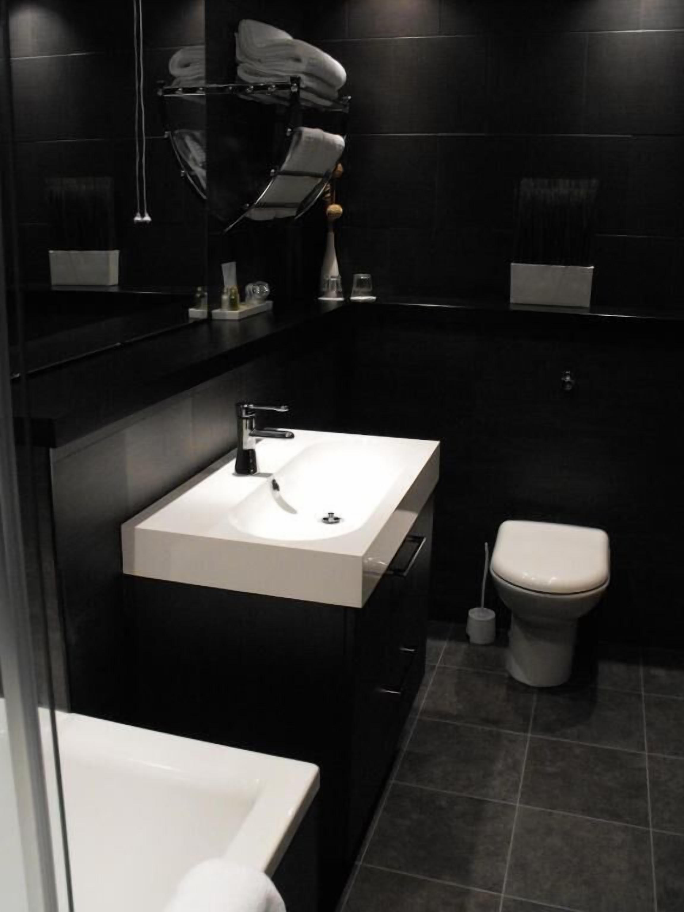 A modern bathroom with a white sink, a toilet, and a shower area.