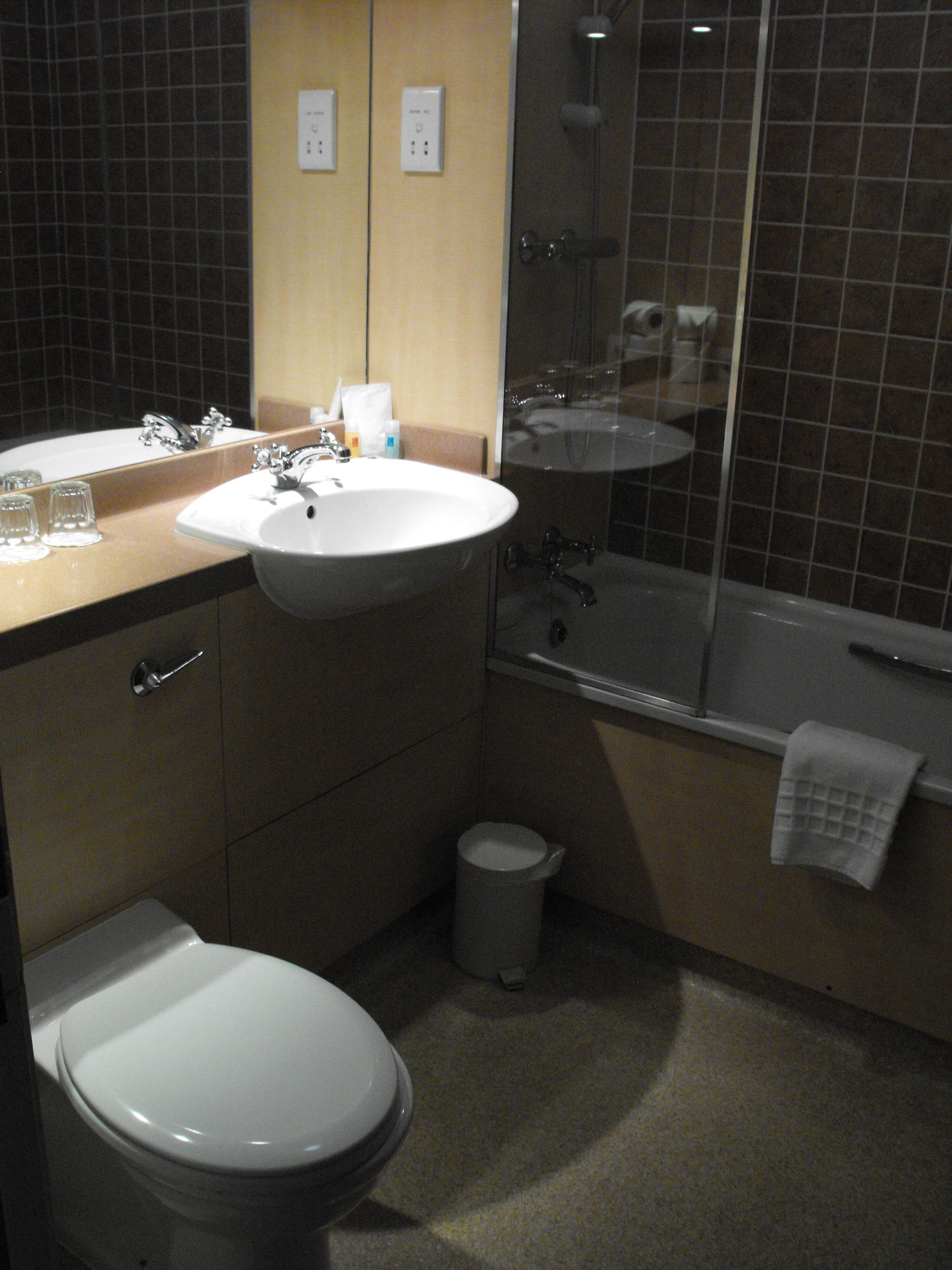Un baño con lavamanos, espejo, inodoro y bañera.