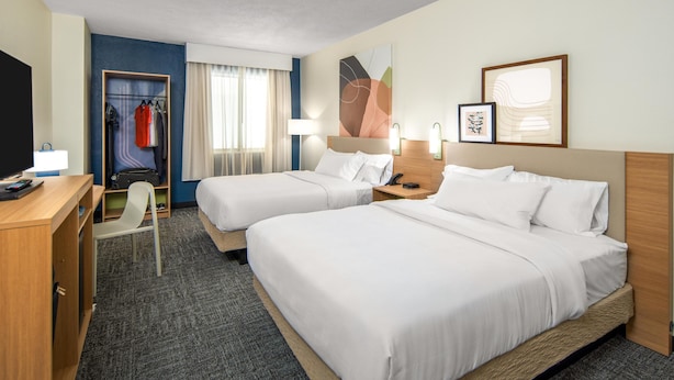 A hotel room with two beds, a desk, a chair, a wardrobe, and a window with curtains. - Spark by Hilton Bloomington (Bloomington)