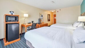 A hotel room with two beds, a desk with a computer, a small refrigerator, and a microwave.