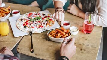 Une table à manger avec une pizza, des frites et des boissons.