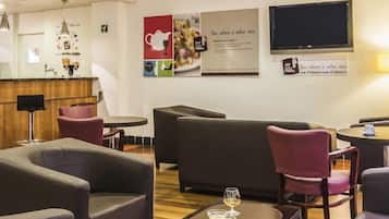 A modern lounge area with comfortable seating, a coffee table, and a television screen mounted on the wall.