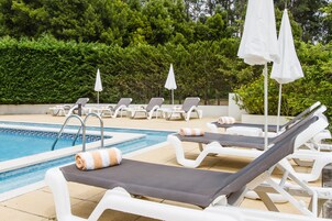 Una piscina al aire libre de temporada, sombrillas, tumbonas