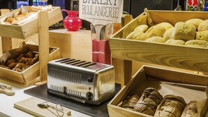 Eine Bäckertheke mit verschiedenen Broten und Gebäck, ein Toaster sowie ein Schild mit der Aufschrift "PADARLA BAKERY BOULANGERIE".