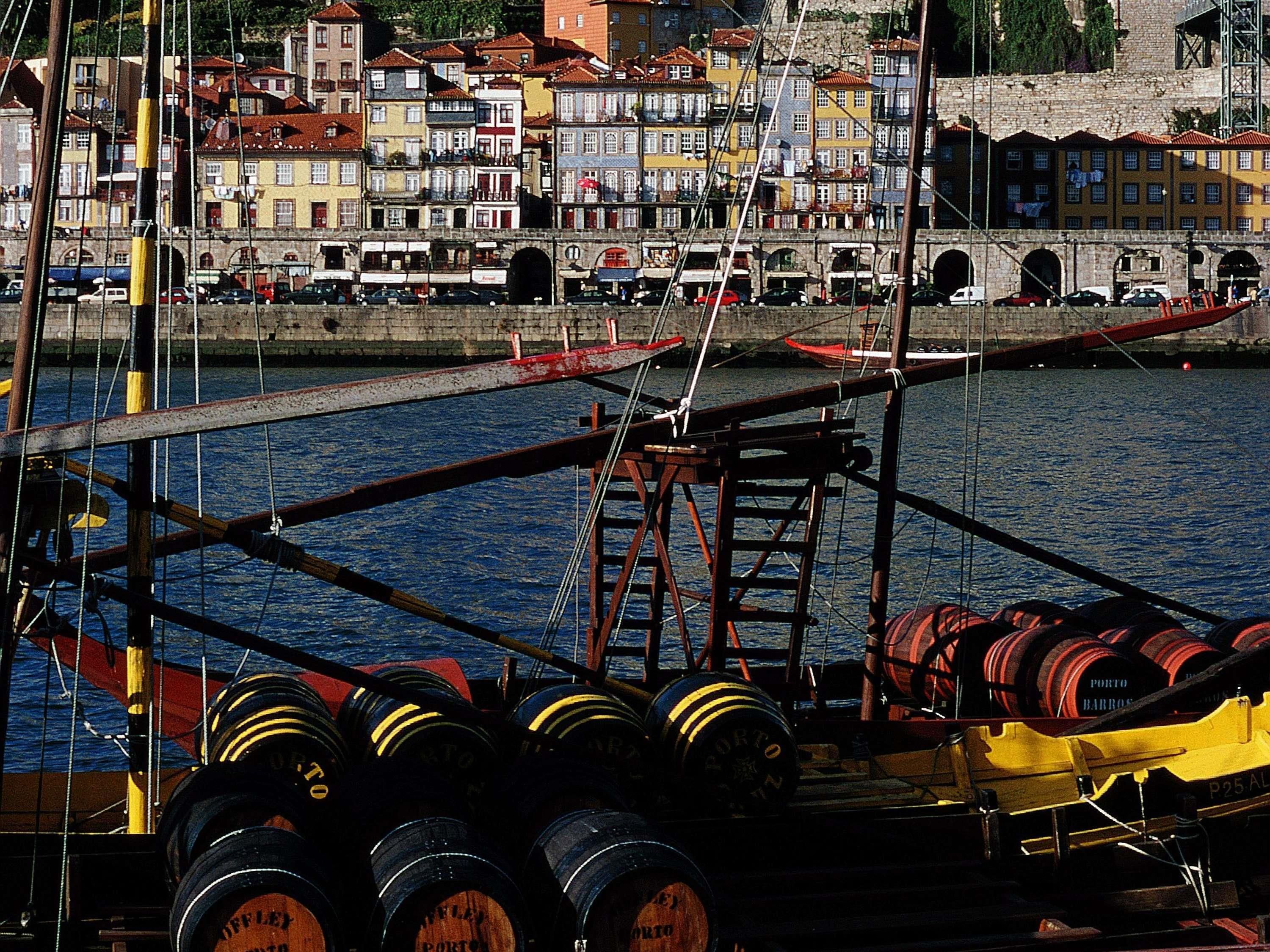 A harbor with boats, barrels, and a cityscape in the background.