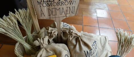A wooden sign with a message, burlap sacks with labels, and wheat stalks.