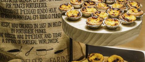 A display of Portuguese egg tarts on a wooden stand and a burlap sack with text.
