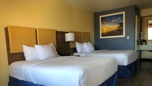 A hotel room with two beds, a nightstand, a lamp, and a painting on the wall.