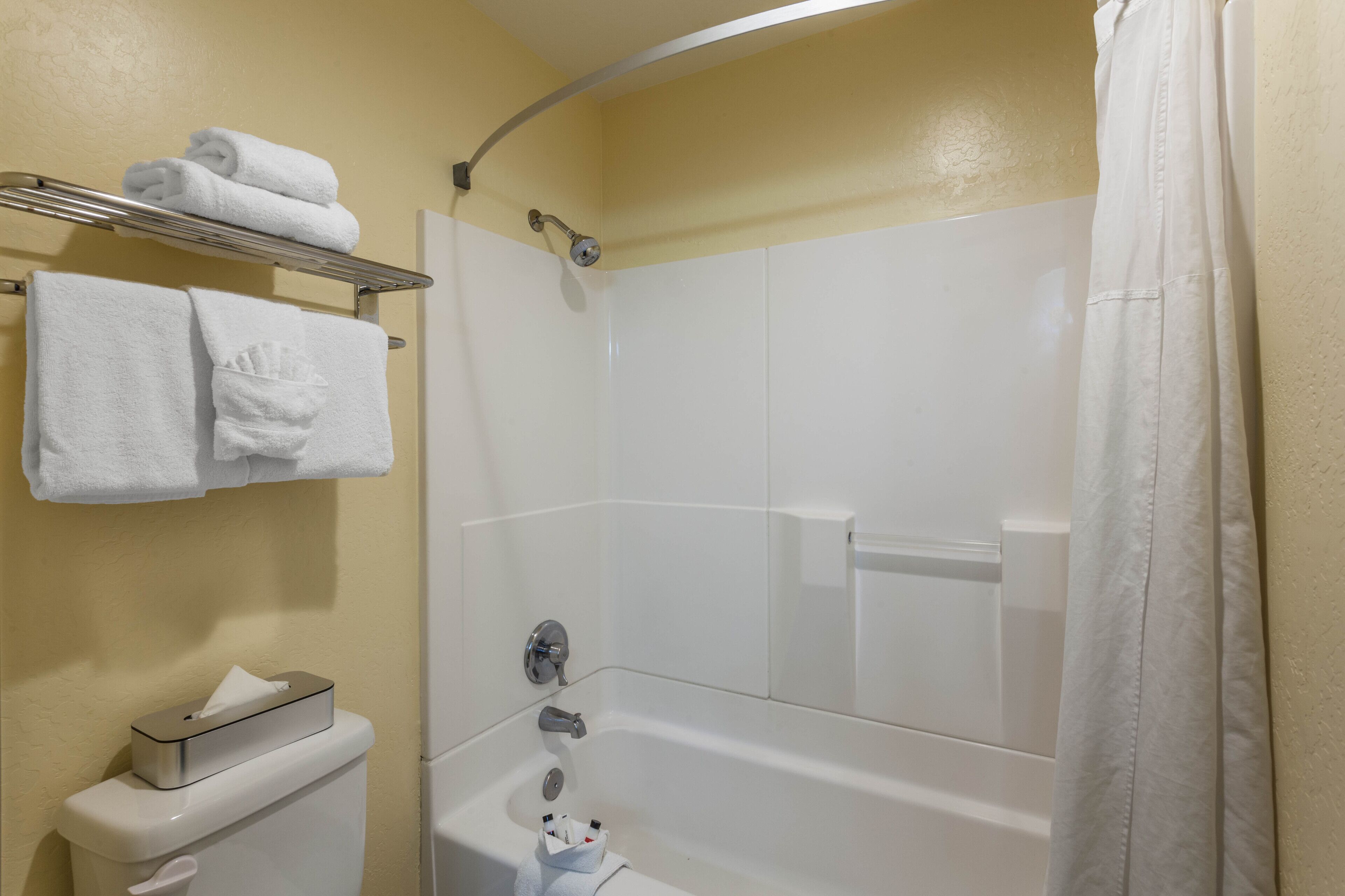 A bathroom with a bathtub, a toilet, and a towel rack with towels.