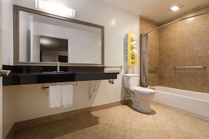 A modern bathroom with a black countertop, a white toilet, a bathtub, and a shower area. - Motel 6 Claremont, CA (Claremont)