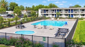 A rectangular swimming pool with a surrounding deck, lounge chairs, and picnic tables. - Motel 6 Claremont, CA (Claremont)