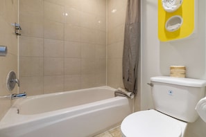 Un baño con bañera, inodoro y un toallero amarillo.