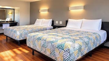Une chambre d’hôtel avec deux lits, un bureau et un miroir.