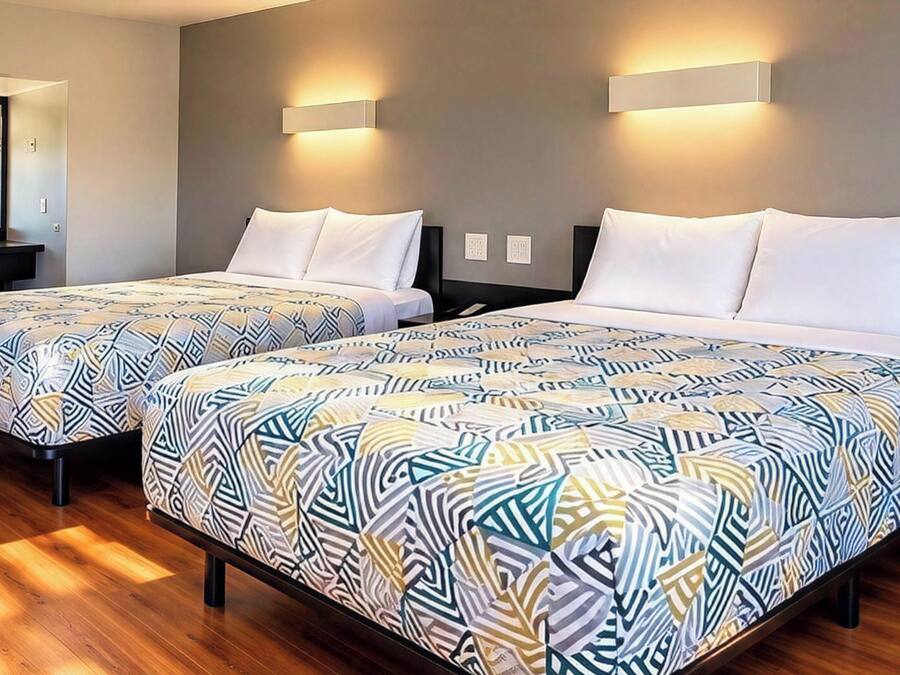 Une chambre d’hôtel avec deux lits, un bureau et un miroir.