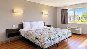 Ett modernt hotellrum med en stor säng, sängbord, ett fönster med gardiner och utsikt över omgivningen.