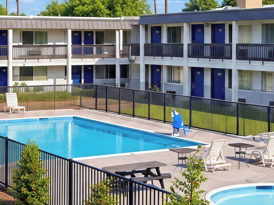 Ett hotell med flera balkonger, en swimmingpool och utomhusmöbler.