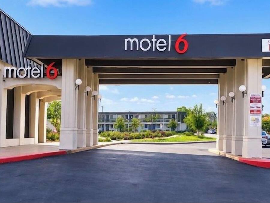Un motel con zona de estacionamiento techada y un letrero que indica una altura máxima de 3.5 metros.